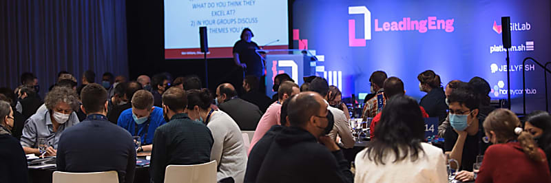 Wide shot of delegates seated at tables at LeadingEng London 2022 with the stage behind